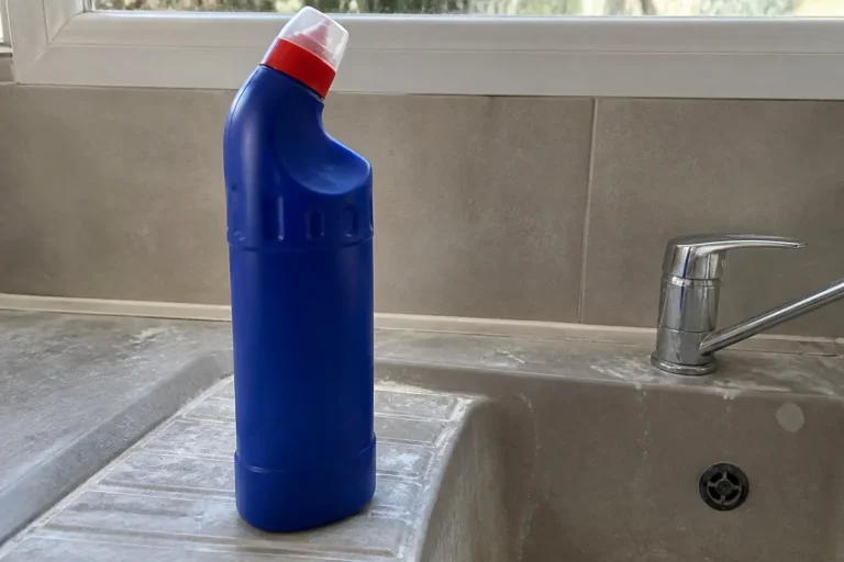 Bouteille bleue posée sur évier, contenant acide chlorhydrique pour WC.