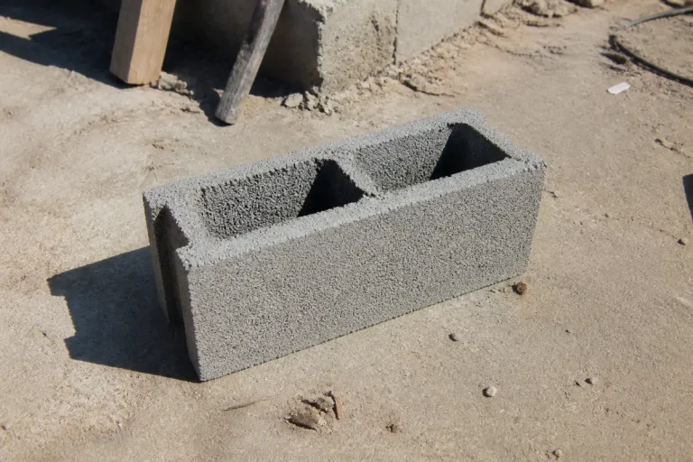 Parpaing sur chantier exposant la hauteur d'un parpaing sur sol sableux