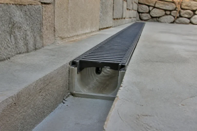 Caniveau installé sans pente le long d'un mur en pierres.