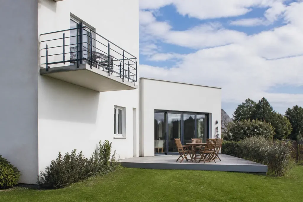 Maison blanche illustrant la différence entre balcon et terrasse avec mobilier extérieur élégant