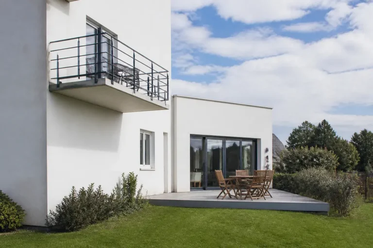 Maison blanche illustrant la différence entre balcon et terrasse avec mobilier extérieur élégant