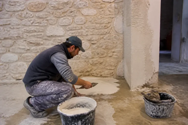 Un artisan enduit un mur en pierre dans un chantier travauxrocket.fr à Paris